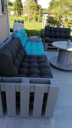 a couch and table sitting on top of a cement floor next to each other in front of a house