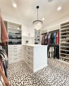 a walk in closet with leopard print flooring and white cabinets, chandelier hanging from the ceiling