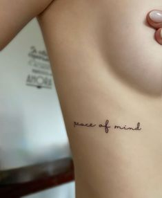 a woman's stomach with the words peace of mind tattooed on her left side