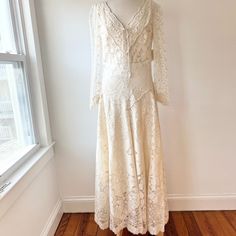 a white dress is hanging on a mannequin in front of a window with a wooden floor