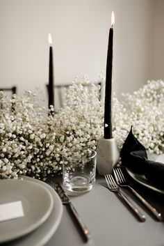 the table is set with silverware and white baby's breath flowers in vases