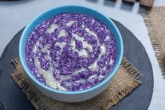 a blue bowl filled with purple rice on top of a black plate