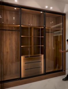 a man standing in front of a closet filled with wooden shelves and glass sliding doors