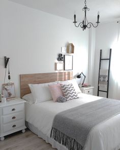 a bedroom with a bed, dresser and chandelier