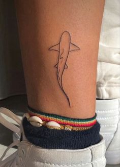 a woman's foot with a tattoo on the ankle and a shark design on it