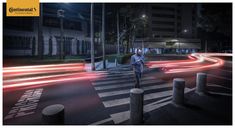 a man standing on the side of a road next to a crosswalk at night