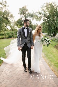 a bride and groom walking down a brick path