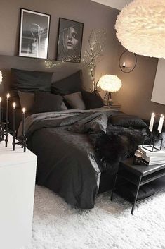 a black and white bedroom with candles on the bed, pictures hanging above the bed