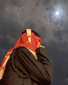 a man wearing a red and white scarf on his head while talking on a cell phone