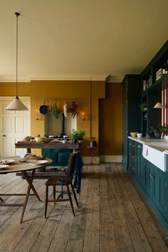 a kitchen with wooden flooring and green cabinets in the center, next to a dining table