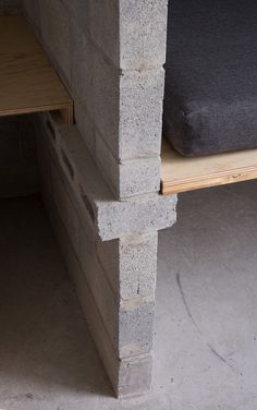 a bench made out of concrete blocks with a cushion on it's back end