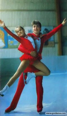 two people dressed in red and white are posing for a photo on the ice rink