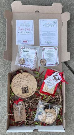 an open cardboard box with various items in it on the ground, including tags and ribbons