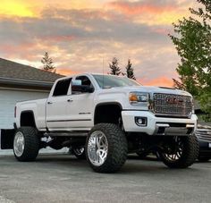 a large white truck parked in front of a garage with the sun setting behind it