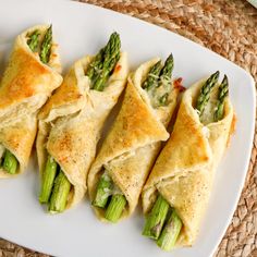 asparagus and cheese filled pastries on a white plate with straw place mat