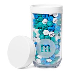 a jar filled with lots of blue and white candies next to a round container