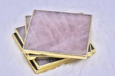 three gold and pink stone coasters on white fur