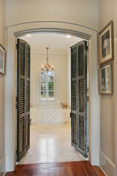 an open door leading to a bathroom with pictures on the wall and wood flooring