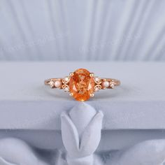 an orange diamond ring sitting on top of a white box