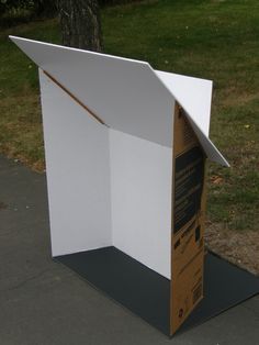 an open cardboard box sitting on top of a black mat next to a tree and grass