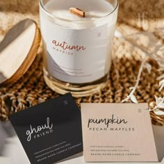 a candle and business cards sitting on a table next to some wood spoons,