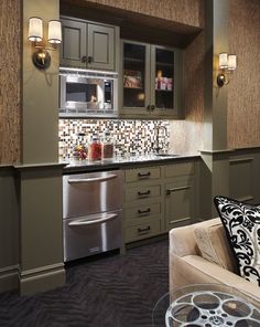 a kitchen with green cabinets and silver appliances in the corner, along with a glass top coffee table