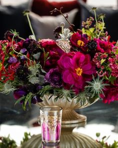 a vase filled with purple and red flowers on top of a table next to two glasses