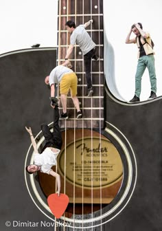 three men are standing on the strings of a guitar