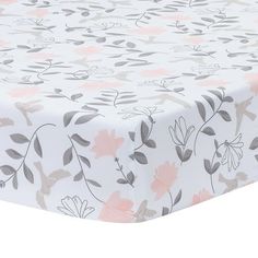 a white sheet with pink and grey flowers on it's side, sitting on top of a table