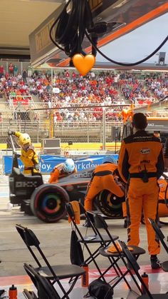 an orange and black race car is on the track with other cars in the background