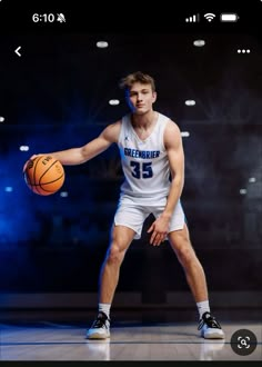 a young man holding a basketball in his right hand and standing on a basketball court