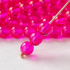 a pink beaded necklace with two beads and a gold bar on the end, sitting in front of a white background