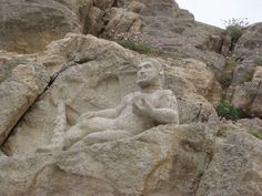 a stone statue sitting on top of a rocky hillside