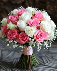 a bouquet of pink and white roses in a vase with baby's breath flowers