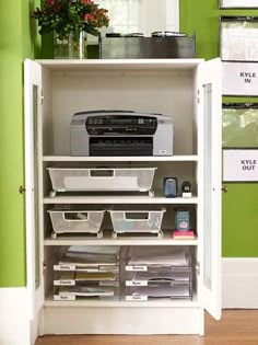 a white cabinet with drawers and printer on it's shelf next to a green wall