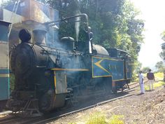 an old fashioned steam engine is on the tracks with people standing around looking at it