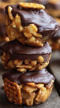 three chocolate covered donuts stacked on top of each other with walnuts and pretzels