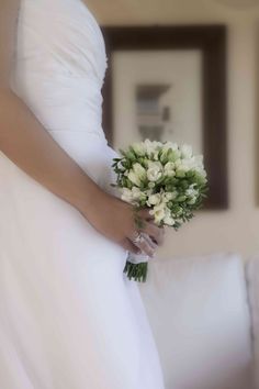 a woman in a white dress holding a bouquet of flowers