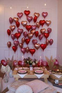 valentine's day table setting with heart balloons on the wall and candles in vases