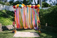 colorful streamers and pom poms decorate the backdrop for an outdoor wedding ceremony