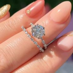 a close up of a person's hand with a ring on their finger and gold nails