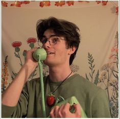 a young man is talking on the phone while holding a strawberry in his hand and smiling