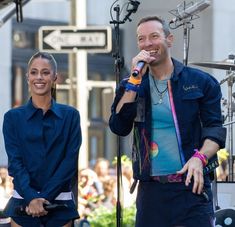 a man standing next to a woman holding a microphone in front of a crowd on stage