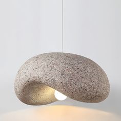 a light that is sitting on top of a stone lamp shade with a rock like structure in the middle