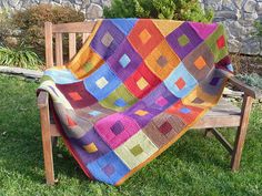 a multicolored blanket sitting on top of a wooden bench