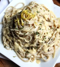 a white plate topped with pasta covered in gravy and lemon zest sauce