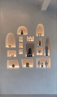 several shelves with various items on them in a white walled room that is lit up