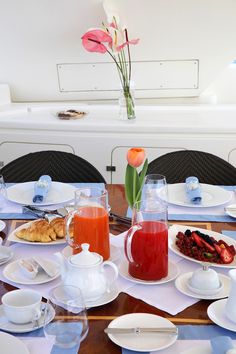 the table is set with plates, cups, and pitchers of juice for breakfast or brunch