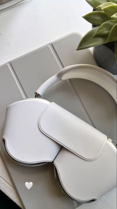 a white handbag sitting on top of a table next to a potted plant