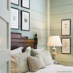 a bed room with a neatly made bed and pictures hanging on the wall above it